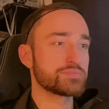 a man with a beard and a headband is sitting in a chair .