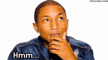 a man in a denim jacket has his hand on his chin and says hmm ...