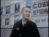 a man stands in front of a wall with a sign that says " союз "