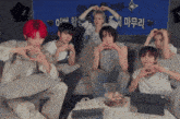 a group of young men are sitting on a couch with their hands in the shape of a heart