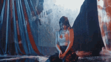 a woman in a white tank top is sitting in a pool of water