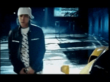 a man wearing a white hat and a black jacket is standing in front of a big bang sign