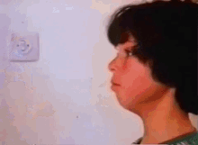 a close up of a person 's face with a light switch behind them
