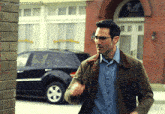 a man wearing glasses stands in front of a brick building with the words supermangifs written on the bottom