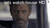 a man with a beard is sitting in a car with the words lets watch house md above him