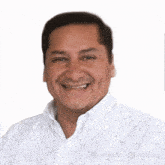 a man wearing a white shirt with polka dots is smiling for the camera