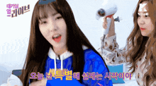a girl in a blue hoodie is holding a hair dryer in her hand