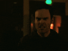 a man pointing a gun at another man with a green exit sign in the background