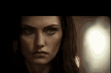 a close up of a woman 's face in a dark room with a blurred background .