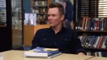 a man is sitting at a table with a stack of books on it