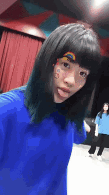 a girl wearing a blue shirt has a rainbow on her face