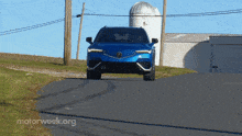 a blue car is driving down a road with motorweek.org in the corner