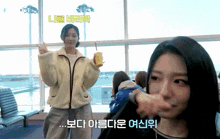 a woman in a white jacket is holding a cup of orange juice and pointing at another woman
