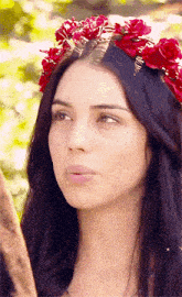 a close up of a woman wearing a crown of red flowers