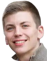a young man is smiling and wearing a sweater