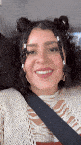a woman wearing a white sweater and a black seat belt smiles
