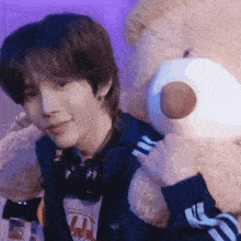 a young man is holding a teddy bear in his arms .