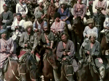 a large group of men are riding horses and one of them is wearing a shirt that says ' a ' on it