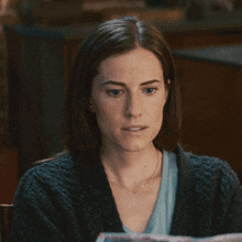 a woman is reading a newspaper and making a face