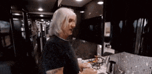 a man with gray hair is standing in a kitchen in a camper van .