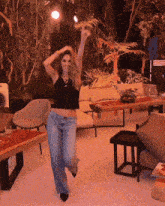 a woman in a black tank top and jeans is dancing