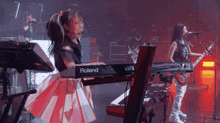 a woman is playing a roland keyboard while another woman plays a guitar