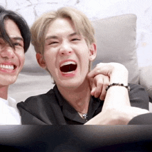 two young men are laughing together and one has a bracelet on his wrist