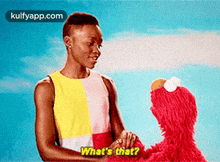 a woman is shaking hands with elmo from sesame street and says what 's that ?