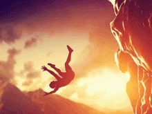 a person is falling from a cliff at sunset