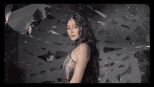 a woman in a dress is standing in front of a wall with broken glass