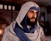 a man with a beard wearing a blue scarf and a white hood