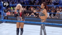 two women are standing in a wrestling ring talking to each other