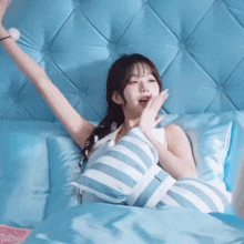 a woman is laying in a bed with her arms outstretched and a striped pillow