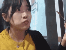 a girl in a yellow sweater is holding chopsticks