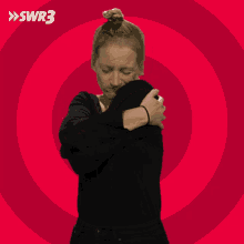 a woman is hugging herself in front of a red background with swr3 written in white