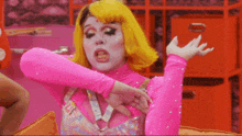 a woman in a pink outfit with yellow hair is making a face
