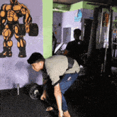 a man lifting a barbell in a gym with a picture of a muscular man on the wall