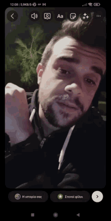 a screenshot of a man 's face on a phone with the time 12:08 on the bottom left