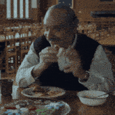 a man is sitting at a table with a plate of food and a bowl of soup