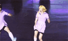 a couple of people are dancing on a stage in purple dresses .