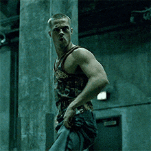 a man in a tank top is standing in a dark room .
