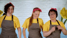 three people wearing aprons are dancing in front of a white brick wall