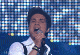 a man singing into a microphone with the number 16 in the corner