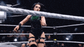 a female wrestler in a black and green outfit is standing in a wrestling ring