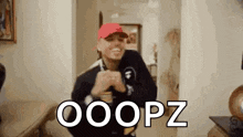 a man in a red hat is dancing in a hallway with the words ooops written on the wall .