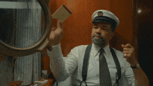 a man in a captain 's hat is holding a piece of paper