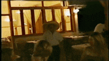 a man wearing a sombrero is standing in a room with people