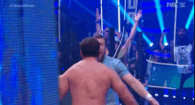 two men are hugging each other in a wrestling match on a stage .