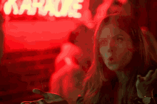 a woman is making a funny face in front of a karaoke sign