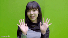 a girl is waving her hands in front of a green screen